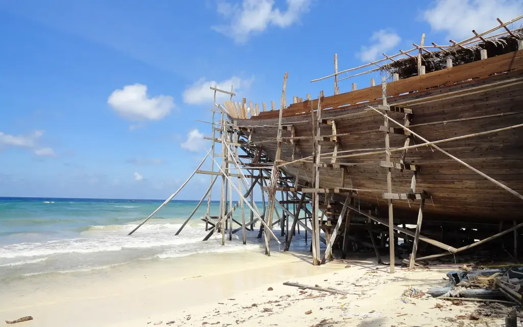 The timber hull of a phinisi under construction on bamboo scaffolding at Tanjung Bira beach, South Sulawesi.