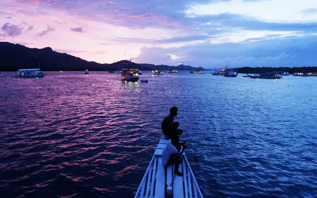A traveller silhouetted on the bow of a boat at dusk off Kalong Island, Labuan Bajo.