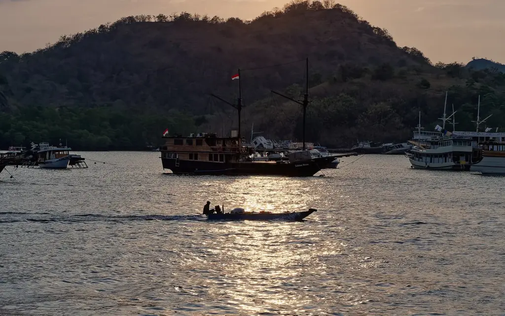 A wooden boat crossing the sun's reflection at sunset off Labuan Bajo, Flores.