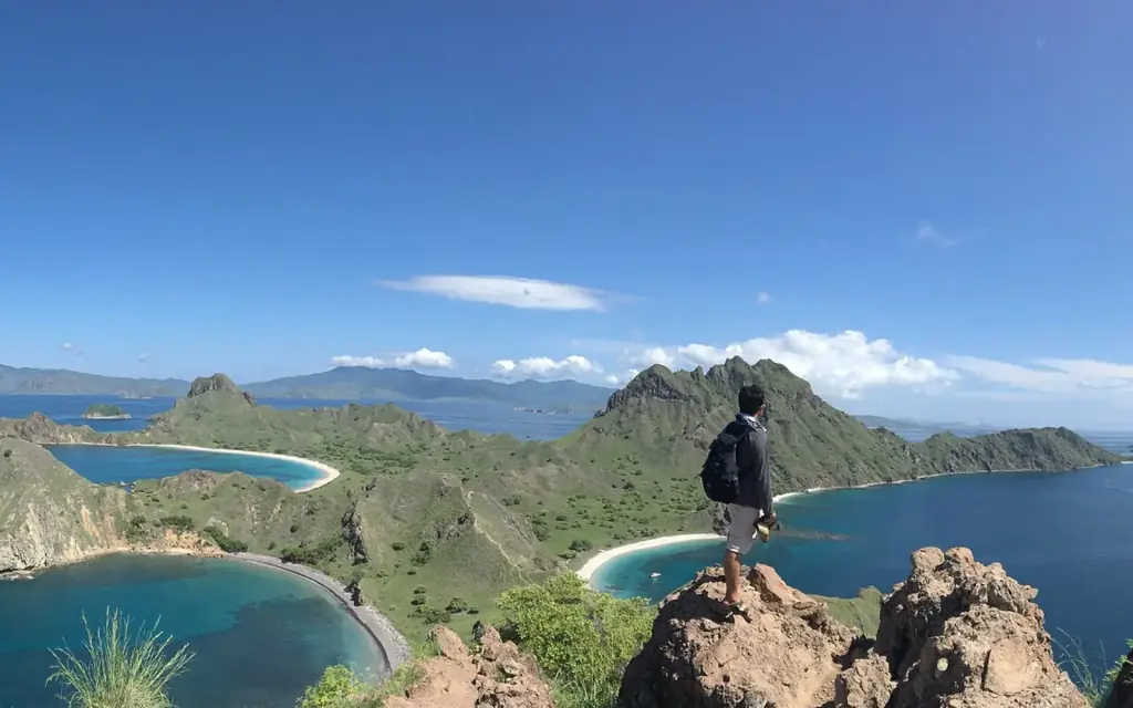 A hiker standing on the rocky Padar Island viewpoint above the island's curving bays.