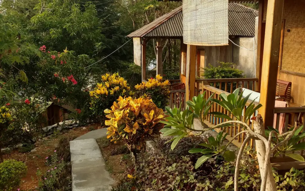 A garden path leading to a timber bungalow with a verandah at a small hotel in Labuan Bajo.