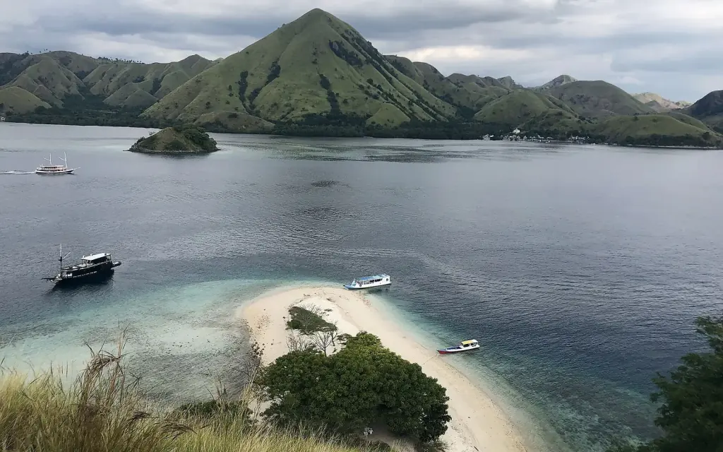 A white sand spit and fringing reef off Padar Island, with small boats anchored in the bay.