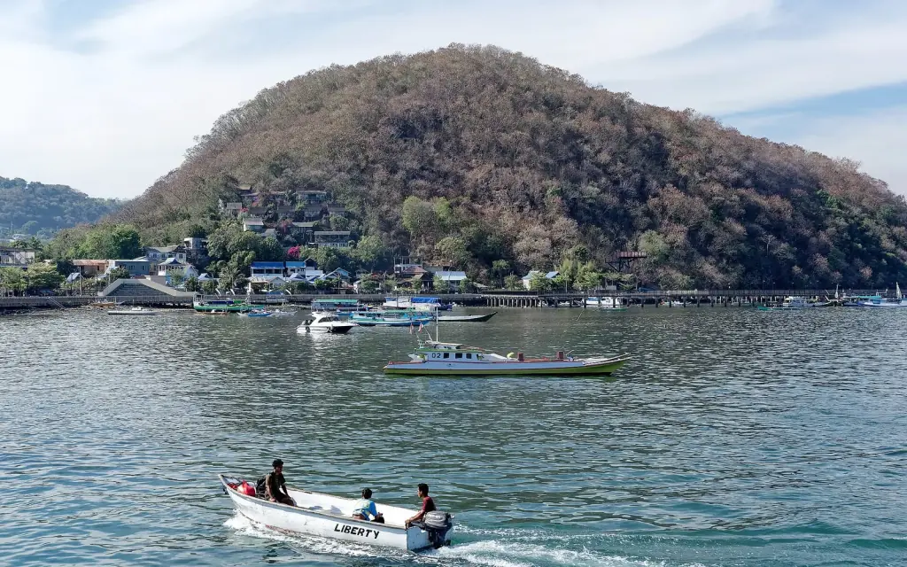 A speedboat running past larger wooden tour boats anchored off Labuan Bajo.