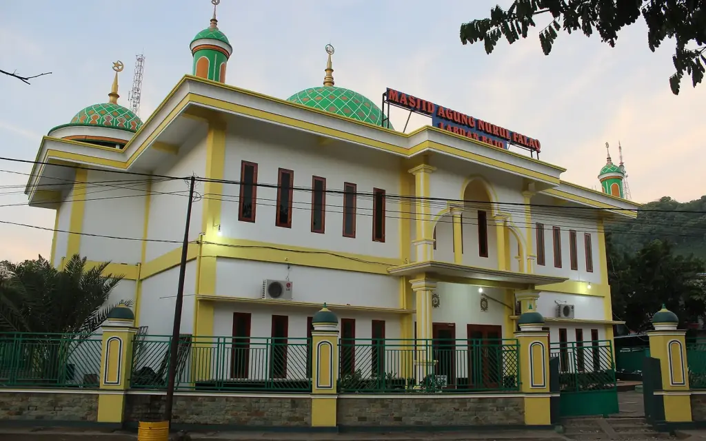 The green-domed Masjid Agung Nurul Falaq lit at night in central Labuan Bajo.