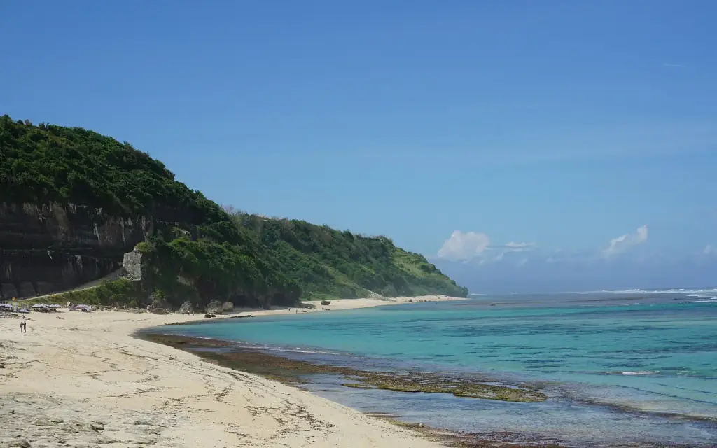 Limestone cliffs above the beach and shallow surf at Pandawa Beach, Bali.